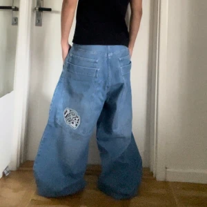 Jinco type baggy jeans - Säljer ett par blå baggy jeans med ett coolt broderi på fickan. De har flera fickor och en bekväm midja. Midjemått: 40cm rakt över, ben längd: ca 110cm och  ben öppning: ca 30cm rakt över