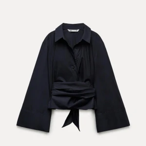 Svart blus med knytband från Zara - Elegant svart blus med knytband i midjan och långa ärmar. Perfekt för en stilren look.