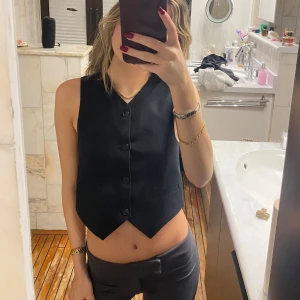 Kostymväst  - Snygg svart väst med knappar framtill. Perfekt för en stilren look och kan enkelt matchas med olika outfits.