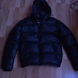 Svart pufferjacka ”Moncler variant” vinterjacka  - Svart puffer jacka från schott. Köpt för 2600 för några månader sedan(just nu slut i alla storlekar i svart). Andra jackor kom mer i användning än denna så därför jag säljer den. Finns inget fel eller något liknande på den(nyskick) För mer frågor kontakta gärna!