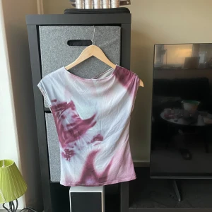 Y2k topp från Motel Rocks - Säljer en cool y2k topp från Motel Rocks i lila och vit. Toppen har en avslappnad passform och korta ärmar, perfekt för en avslappnad stil. Den unika färgkombinationen ger en trendig look.