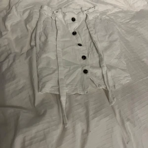 Vit linneblandad kjol med knappar - Snygg vit kjol i linneblandning från H&M. Kjolen har stora knappar framtill och ett knytband i midjan för en justerbar passform. 