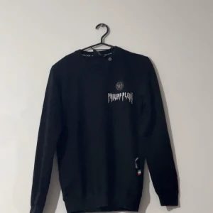 Svart tröja från Philipp Plein - Snygg svart tröja från Philipp Plein med logotyp på bröstet. Tröjan har långa ärmar och en klassisk passform. Perfekt för en stilren look.