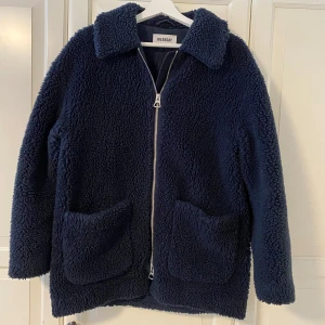 Mörkblå teddyjacka från Weekday - Säljer en mysig mörkblå teddyjacka från Weekday. Jackan har en dragkedja framtill och två stora fickor. Perfekt för kalla dagar då den är rymlig och man får plats med en tjock tröja under, men funkar även super på våren och hösten tillsammans med tunnare tröjor. 