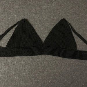 Svart ribbad bralette  - Snygg svart bralette med ribbad textur och knytband. Perfekt för en dag på stranden eller vid poolen. Triangelformade kupor ger en klassisk look.