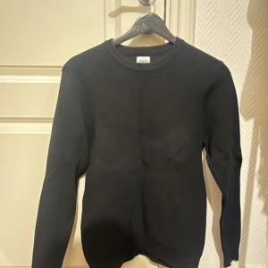 Svart tröja från Zara - Säljer en stilren svart tröja från Zara. Tröjan har en klassisk design med rund hals och långa ärmar, perfekt för en minimalistisk look. Passar bra till både jeans o andra byxor.