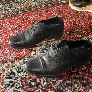 Svarta skor  - Snygga svarta skor  i skinn med elegant snörning. Perfekta för en stilren look. Sulan har ett bra grepp och skorna är i storlek 41.