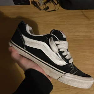 Vans knu skool  - Säljer ett par klassiska svarta och vita Vans sneakers med snörning. Skorna har den ikoniska vita sidostripen och en bekväm passform. Perfekta för en avslappnad stil. Pris kan diskuteras!
