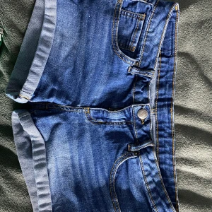 Lågmidjade shorts - Snygga blå jeansshorts med klassisk femficksdesign och uppvikta benslut. Perfekta för en avslappnad stil. Dessa shorts är ganska lågmidjade