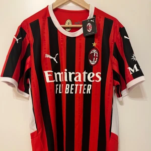 AC Milan fotbollströja från Puma 2024/25 - Snygg AC Milan fotbollströja i rött och svart med vita detaljer. Tröjan är kortärmad och har klubbens emblem samt Puma-logga på bröstet. Perfekt för fans av laget! Oanvänd och etikett kvar. Tröjan är i xl men passar även L