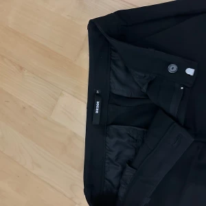 Svarta kostymbyxor från Bikbok - Snygga svarta lågmidjade kostymbyxor från Bikbok med bootcut. Jättefint skick!
