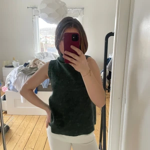 Mörkgrön ärmlös polotopp - Säljer en stilren mörkgrön ärmlös polotopp. Perfekt för lager-på-lager eller att bära som den är. Toppens material är mjukt och bekvämt, vilket gör den idealisk för både vardag och speciella tillfällen.