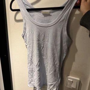 Ljuslila ribbad linnetopp från Gina Tricot - Säljer en ljuslila ribbad linnetopp från Gina Tricot. Perfekt för varma dagar med sin ärmlösa design och mjuka material. Enkel och stilren för en avslappnad look.