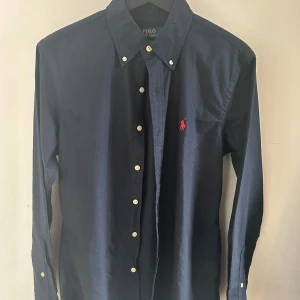Ralph lauren skjorta - En super fin mörkblå Ralph lauren skjorta som bara använts en eller två gång sen jag köpte den på Harrods i somras så 10/10 skick. 
