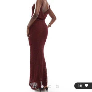 Vinröd glittrig långklänning - Elegant vinröd långklänning med glittrande detaljer. Klänningen har en smickrande passform och är ärmlös med en vacker drapering vid halsen. Perfekt för festliga tillfällen. Lätt genomskinlig. ENDAST PROVAD