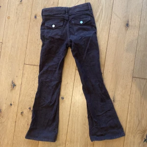 Bruna manchesterbyxor - Snygga bruna manchesterbyxor med bootcut-stil. Byxorna har fickor med knappar bak och en klassisk design framtill. Perfekta för en avslappnad look.