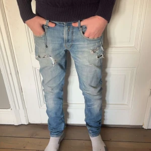 Ljusa slitna jeans från Replay - Säljer ett par ljusa jeans från Replay med slitna detaljer och en avslappnad look. De har en klassisk femficksdesign och en bekväm passform. Storlek är W29 L32