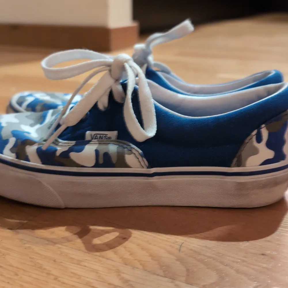 Snygga Vans sneakers i blått och kamouflagemönster. Skorna har klassisk snörning och en vit sula. Perfekta för en skater stil och storlek jr 35.. Kengät.