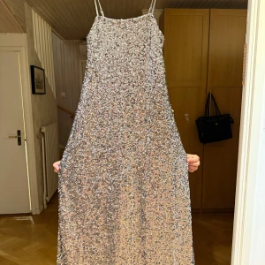 Glittrig klänning från Kappahl - Säljer en glittrig klänning från Kappahl med smala axelband. Perfekt för en festlig kväll med sitt skimrande material som fångar ljuset vackert.