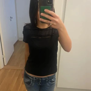Topp med spets - Snygg svart topp med spetsdetaljer vid axlarna och halsen. Toppen har korta ärmar och en normal passform. Ganska bra skick, bara lite nopprig men inget man lägger märke till så mycket eftersom att det typ bara syns från nära håll om man kollar noggrant☺️