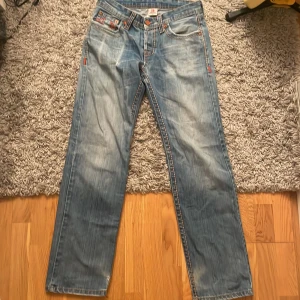 True Religion - True Religion jeans med röda sömmar. Fint skick förutom ett litet hål i höger ficka och markering efter mobilen. 21cm i benöppning och 83cm i innerbenslängd