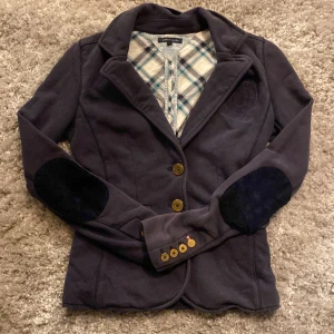 Mörkblå kavaj från Tommy Hilfiger - Snygg mörkblå kavaj från Tommy Hilfiger med rutigt foder och eleganta knappar. Kavajen har långa ärmar och stiliga armbågslappar i mörkare ton. Perfekt för en stilren look. Nypris ~ 800 mitt pris: 100