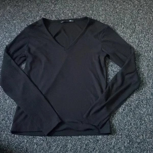 Svart långärmad tröja med v-ringning - Snygg och stilren svart tröja med v-ringning och långa ärmar. Perfekt för en enkel och elegant look.