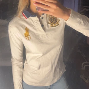Vit rugbytröja från Ralph Lauren - Säljer en stilren vit rugbytröja från Ralph Lauren med vintagestil. Den har broderad logga och nummerdetalj. Tröjan har långa ärmar och en klassisk krage med knappar🏇. Rugbytröjor trendar just nu (se bild 5 för inspo). Storlek M/M men tycker den är liten i storleken.🤍 kom med prisförslag😆