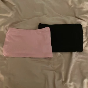 Två tub toppar i rosa och svart - Säljer två stilrena tub toppar i rosa och svart. Perfekta för en trendig look. De är ganska stora i storleken så passar M också💗