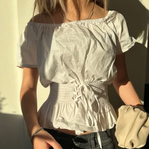 Vit offshoulder blus med knytning - Säljer en söt vit offshoulder blus med korta ärmar och knytning i midjan!! 😘