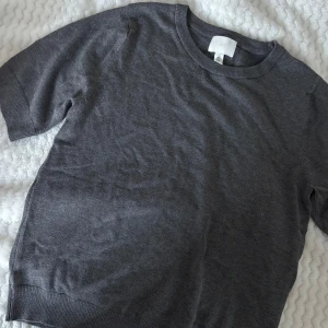 Grå tröja från H&M - Säljer en stilren grå tröja från H&M. Tröjan har korta ärmar och en rund halsringning. Aldrig använd! 