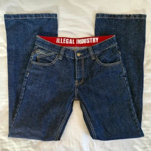 Lågmidjade bootcut-jeans - Supercoola jeans från Illegal Industry! 🖤 Darkwash, utsvängda och lågmidjade med asymetriska fickor framtill.  Använda men i fint skick! Pris är förhandlingsbart :) Midjemått: 80 cm Totallängd: 108 cm Innerbenslängd: 81 cm Benvidd nedtill: 26 cm 