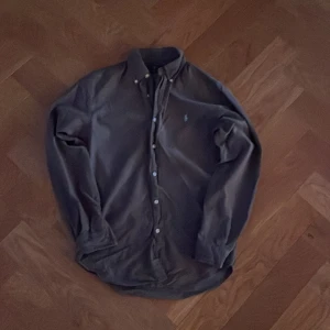 Mörkblå skjorta från Ralph Lauren - Snygg mörkblå skjorta från Ralph Lauren i slim fit. Skjortan har långa ärmar och knappar framtill. Perfekt för en stilren look.