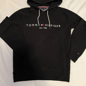 Svart Tommy Hilfiger hoodie Storlek Medium - En svart Tommy Hilfiger hoodie i storlek Medium i bra skick. Tveka inte på att höra av dig om du har frågor eller är intresserad!