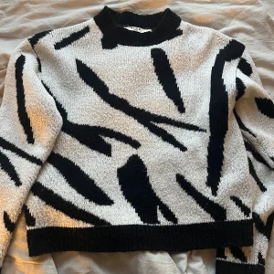 Svartvit mönstrad tröja från NA-KD - Säljer en cool svartvit tröja från NA-KD med ett djärvt mönster. Tröjan har långa ärmar och en rund halsringning. 