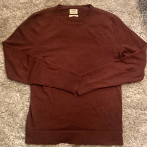 Röd merinoulltröja från Jack & Jones - Säljer en stilren röd tröja från Jack & Jones i 100% merinoull. Perfekt för kyliga dagar med sin mjuka och värmande kvalitet. Tröjan har långa ärmar och en klassisk passform. Den är i bra skick förutom att den är lite nopprig. Skriv gärna över frågor och funderingar, priset kan diskuteras.