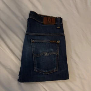 Nudie Jeans - Säljer dessa feta Jeans från märket Nudie i mörkblå färg med snygga vita detaljer på bakfickorna. Byxorna är i storlek W|32 L|32🔥 Modellen heter Thinn Finn och sitter riktigt fint!🙌