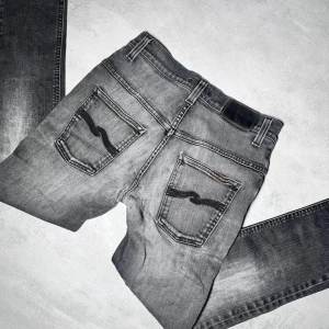 Grå jeans från Nudie Jeans -  Grå jeans från Nudie Jeans med slitningar. Modell: Thin fin, helt okej skick, har blivit lagade hos nudie, W29 L32