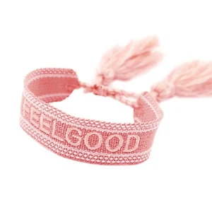Rosa armband  - Charmigt rosa armband med texten 'FEEL GOOD'. Armbandet har en flätad design med tofsar i ändarna, vilket ger en bohemisk känsla. Perfekt för att lägga till en färgklick till din outfit.