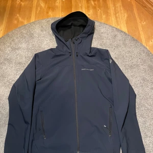 Mörkblå vindjacka från Peak Performance - Säljer en stilren mörkblå vindjacka från Peak Performance. Jackan har en praktisk huva och dragkedja framtill. Perfekt för kyligare dagar med sin långa ärmar och bekväma passform. Perfekt för våren/hösten. Storlek (S). Nypris 2500 medan jag säljer den endast för 600kr. Skriv för minsta lilla fråga/ fundering 😃