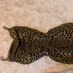 Leopardmönstrad klänning från NA-KD - Trendig leopardmönstrad klänning från NA-KD med smala axelband. Perfekt för en djärv look. Klänningen har en figurnära passform och är tillverkad i ett mjukt material.