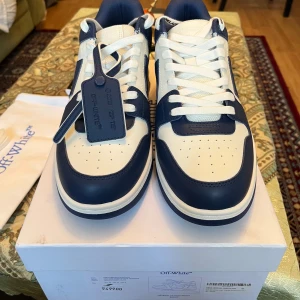 Off-White sneakers i vitt och blått - Säljer ett par snygga Off-White sneakers i vitt och blått. Skorna har en cool design med snörning och är gjorda i skinn. Perfekta för att ge din outfit en stilren touch. De kommer i originalförpackning och är i nyskick.