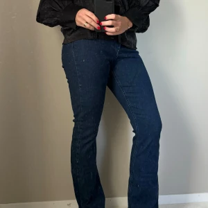 Mörkblå jeans med bootcut - Säljer ett par snygga mörkblå jeans med bootcut. De har en tight passform upptill och blir vidare nedtill, vilket ger en riktigt schysst siluett. Perfekta för både vardag och fest!