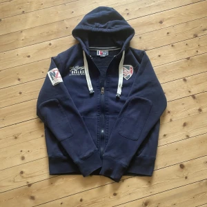 Mörkblå hoodie med tryck - Säljer en mörkblå zip hoodie från DEELUXE. Den är i storlek L. Den är för stor för mig så kommer sitta bättre på dig som har storlek L. 