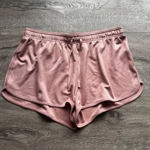 Rosa shorts med dragsko - Säljer ett par superbekväma rosa shorts med dragsko i midjan. Perfekta för en avslappnad dag eller träning. De har en loose passform och är gjorda i ett mjukt material som känns skönt mot huden.