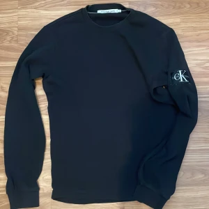 Svart långärmad tröja från Calvin Klein Jeans - Säljer en stilren svart långärmad tröja från Calvin Klein Jeans. Tröjan har en enkel design med CK-loggan på ärmen. Perfekt för både vardag och fest. Är väldigt skön att ha på sig, tröjan är i perfekt skick 10/10