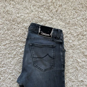 Jacob Cohen jeans - Ett par mörkgråa snygga Jacob Cohen jeans, handsydda från Italien! Storlek 32. Har en liten slitning vid märket på baksidan som syns i bild 1!