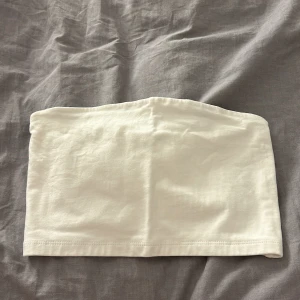 Vit topp utan band - En vit topp utan band. Toppen är väldigt kort och är ancvänd ett par gånger. Dock är toppen i god skick. Storleken är XS.