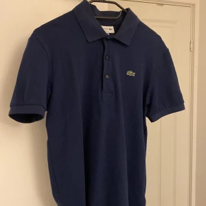 Lacoste piké  - En marinblå Lacoste piké i topp skick!