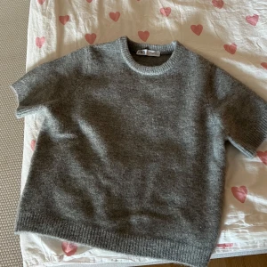 Stickad grå T-shirt  - Jättefin stickad grå t-shirt. Är normalt storlek S men tycker den sitter lite för tight så skulle rekommendera den till någon som normalt är xs eller om man tycker om att den sitter tight. Har aldrig använt den pågrund av att den är för liten. 